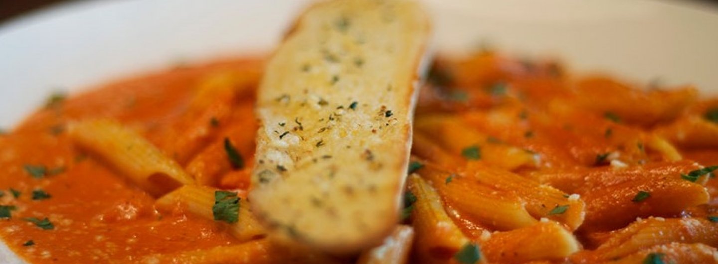 red sauce pasta with a stick on garlic bread ontop