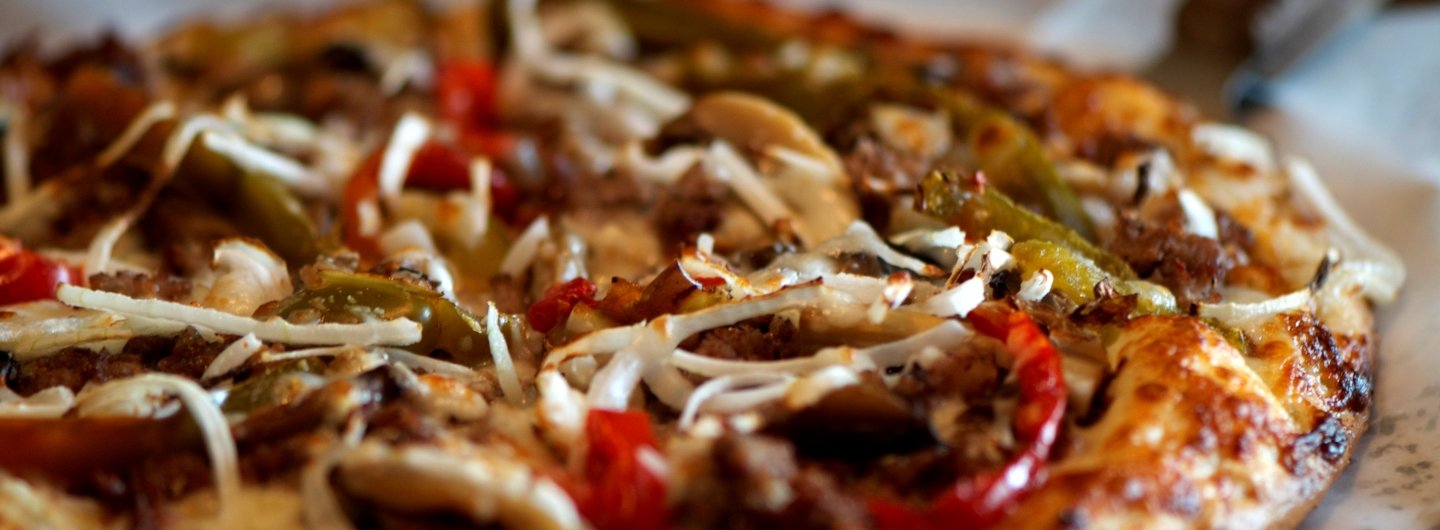 cheese pizza topped with steak, green and red peppers and onions